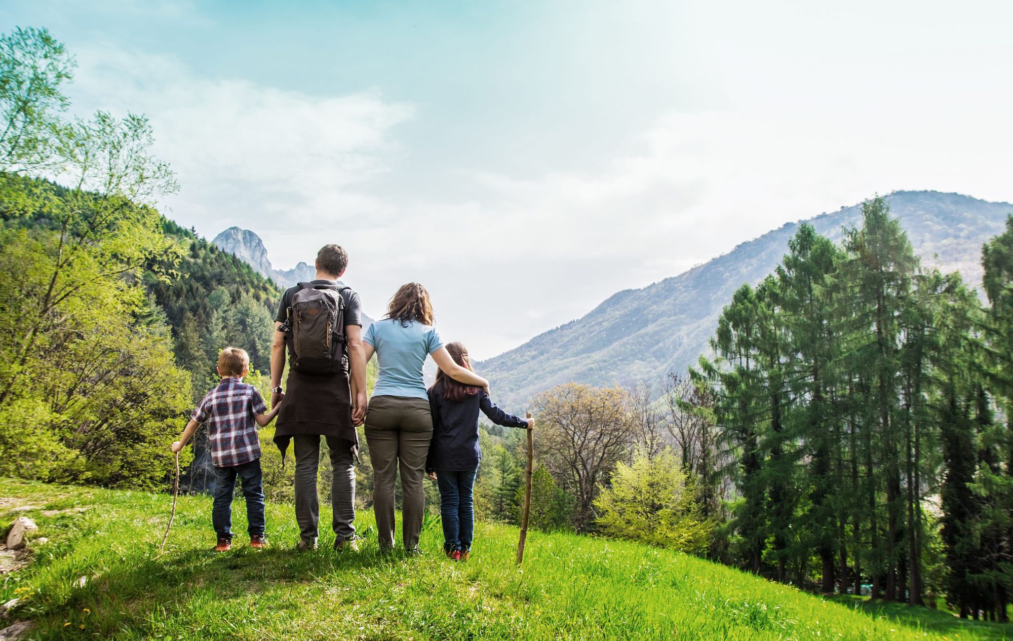 Family On A Green Meadow Looking At The Mountain Panorama